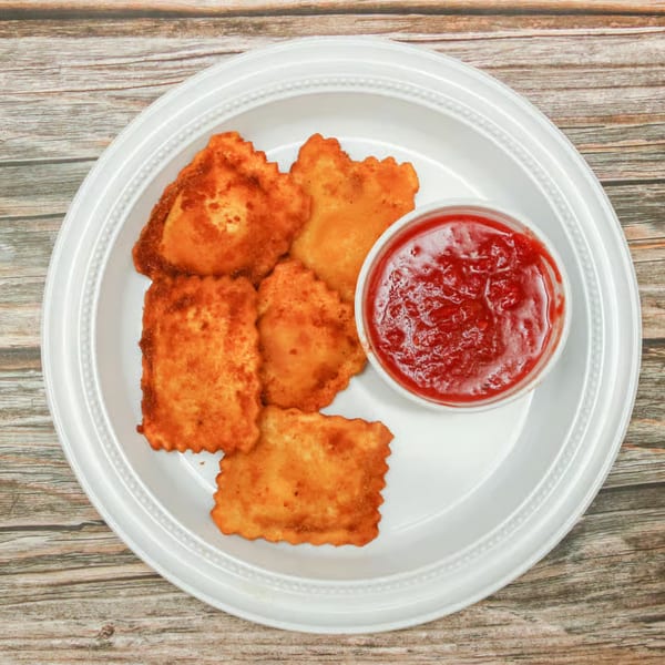 Fried ravioli with a side of marinara sauce on a white plate from Cosmic Pizza Steak & Wieners.